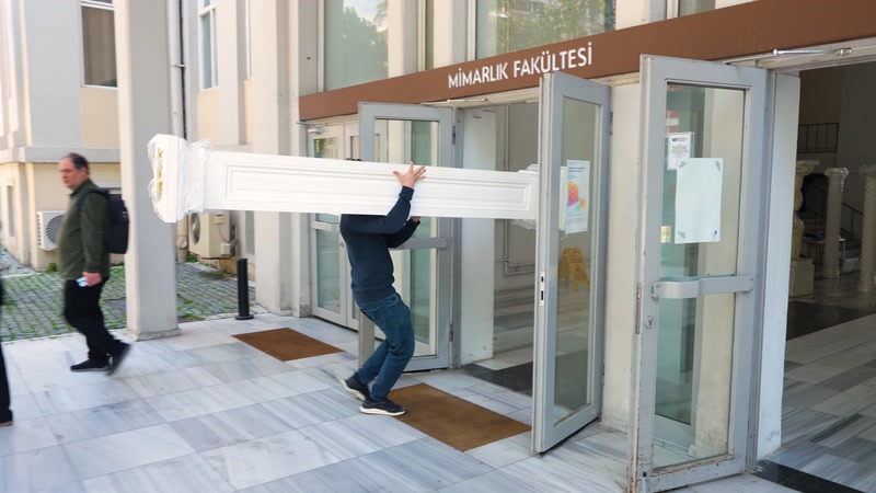 Uzun dekoratif profil etkinlik alanına iki kişi tarafından taşınıyor
