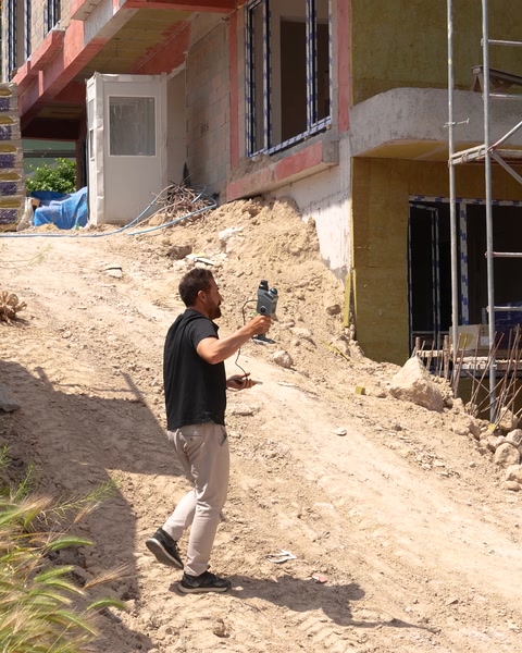 Şantiye yamacında teknisyen elinde cihazla tarama yapıyor