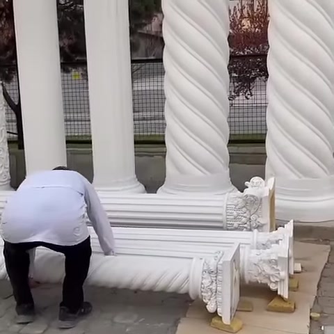 Usta, yerdeki uzun dekoratif sütun parçalarının yanına eğiliyor