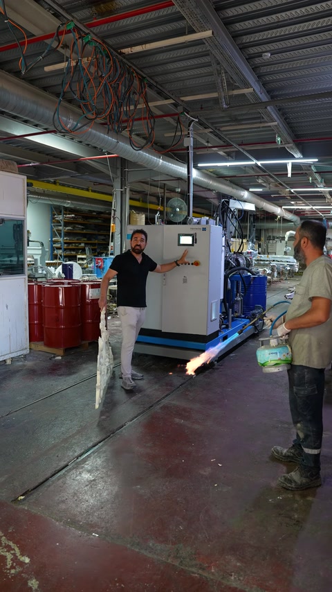Fabrika ortamında yeni üretim makinesi ve çevresindeki ekipmanlar tanıtılıyor.