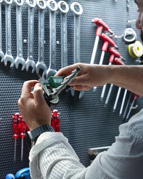 Yakın çekimde eller CNC makinesi kumandasını tutuyor