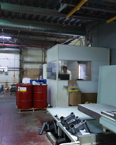 Fabrika içinde CNC tezgahları ve depolama fıçıları görünüyor