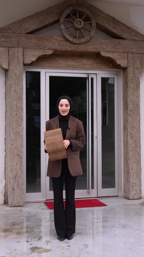 Sunucu, giriş önünde ahşap dokulu kiriş numunesini sergiliyor