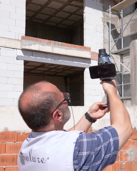 Teknisyen pencere boşluğu yanında cepheyi tarayıcıyla ölçüyor