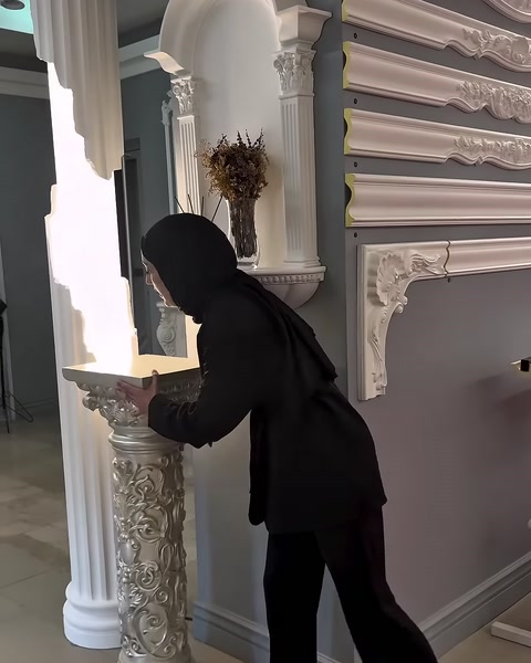 Oyma görünümlü süslü sütun ayağı raf yanında inceleniyor