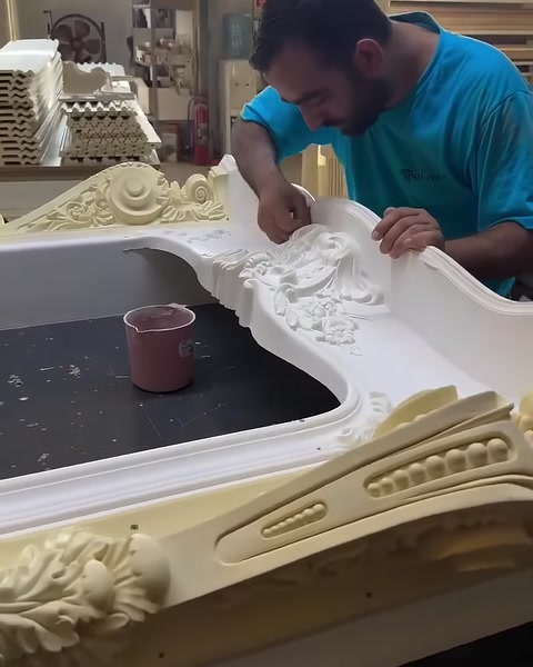 Beyaz şömine çerçevesi, süslemeli yan parçalar arasında hazırlanıyor.