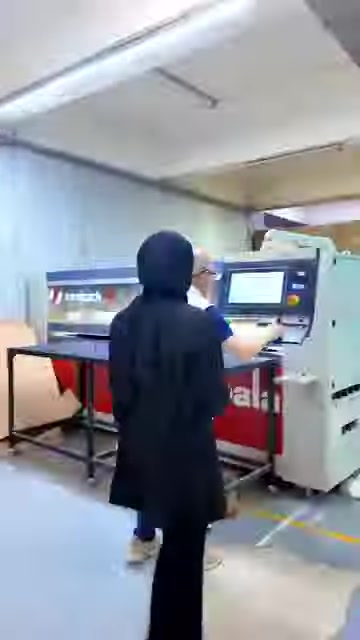 Üretim tesisindeki bilgisayar kontrollü makine ve çalışma alanı gösteriliyor.