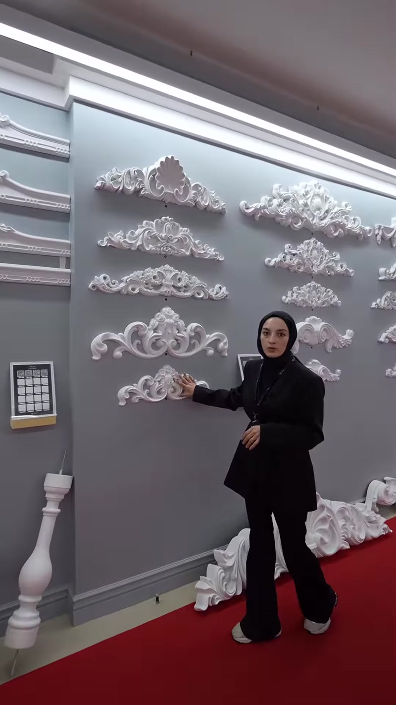 Çiçekli ve kıvrımlı poliüretan taç motifleri sergileme duvarını kaplıyor