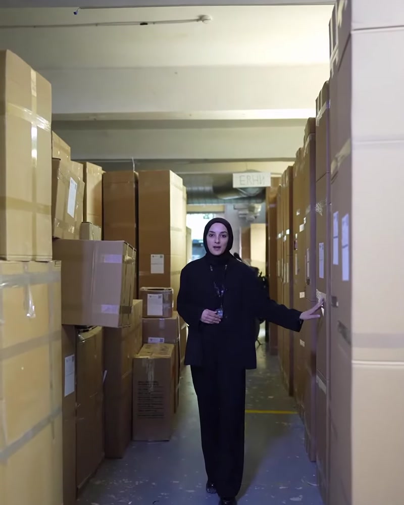 Karton kolilerle dolu depo koridorunda paketleme süreci tanıtılıyor