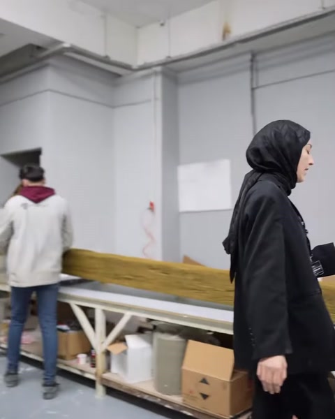 Görevli, uzun çalışma tezgâhının bulunduğu paketleme bölümüne ilerliyor