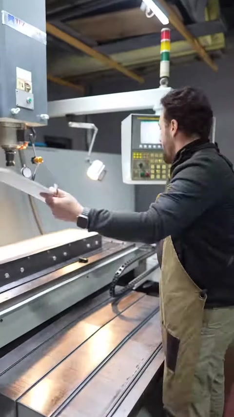 Operatör uzun beyaz panel parçasını tezgahtan dikkatlice kaldırıyor