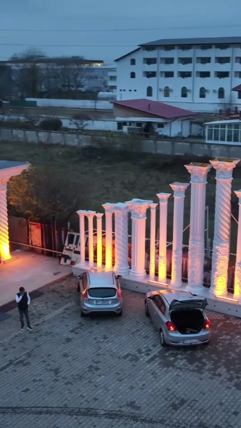 Farklı biçimlerde sütunlarla düzenlenen aydınlatmalı çevre duvarı