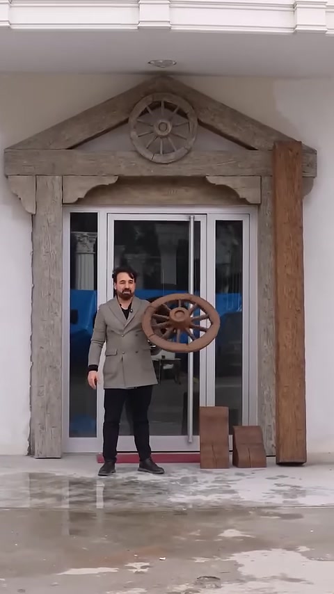 Rustik giriş uygulaması önünde dekoratif ahşap görünümlü tekerlek sergileniyor