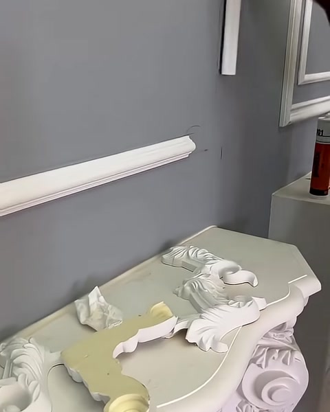 Gri uygulama duvarında beyaz çıtalar ve masadaki motifler görülüyor.
