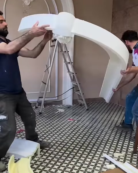 Esnek kemer parçası iki kişi tarafından biçimlendirilerek taşınıyor