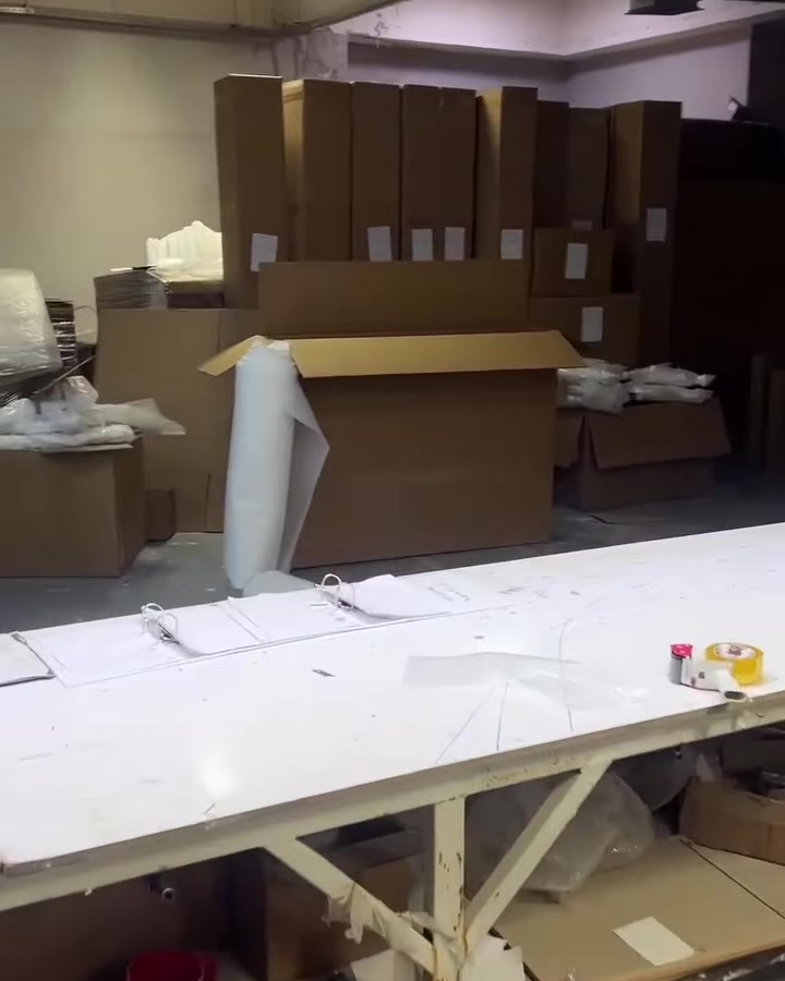 Atölyede çalışma masası ve paketlenmiş uzun dekoratif parçalar bulunuyor