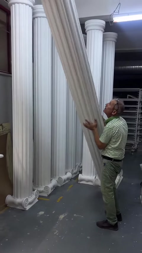 Çalışan uzun dekoratif sütunu dik konumdan eğerek taşıyor
