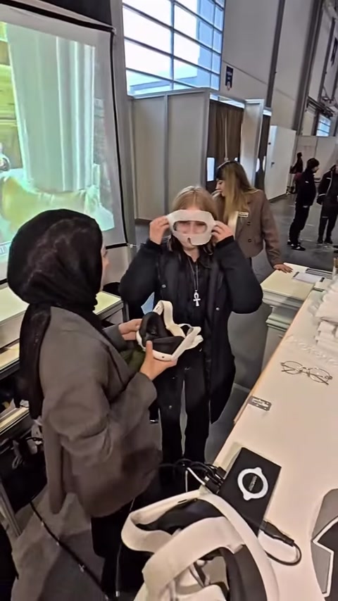 Görevli, VR gözlüğünü ziyaretçinin kullanımı için hazırlıyor.