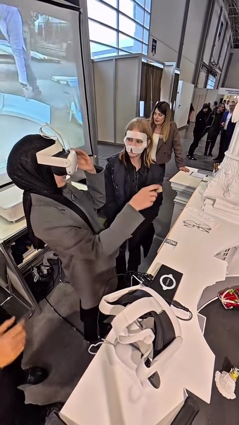 Ziyaretçiye mimari maketi deneyimlemesi için VR gözlüğü takılıyor.