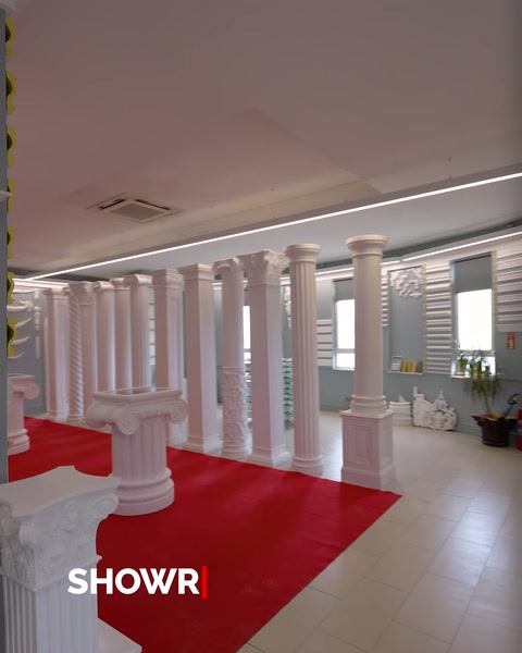 Kırmızı halılı showroom koridorunda dizili poliüretan sütunlar