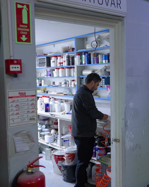 Laboratuvar kapısından raf dizisi ve çalışan arka planda görünüyor