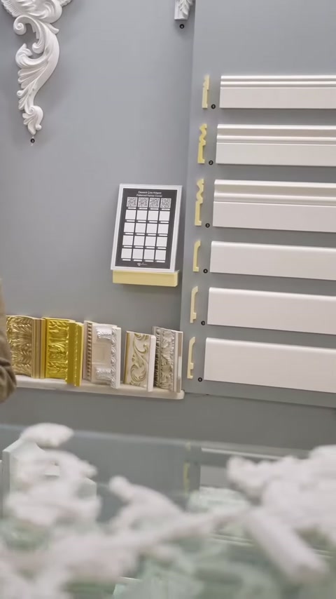 Duvarda yatay çıta profilleri ve çerçeveli ürün panoları sergileniyor.