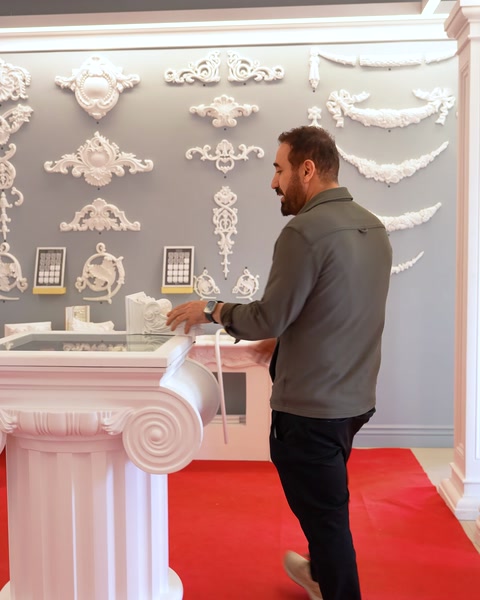 Showroom içinde beyaz sütun kaidesi yanında duran erkek