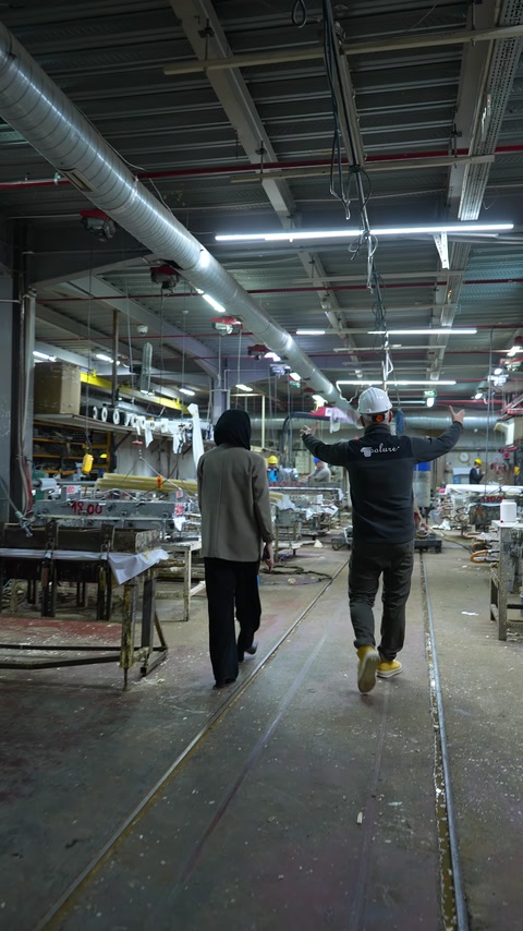 Geniş üretim hattında çalışanlar ve fabrika ekipmanları yer alıyor