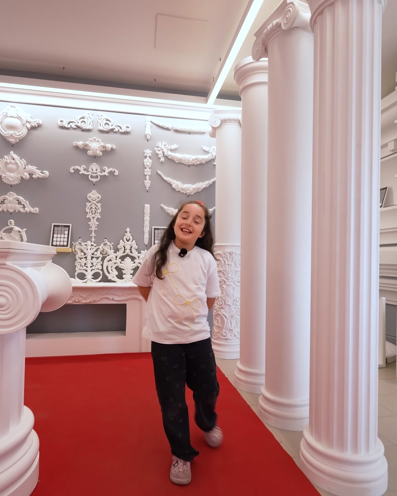 Uzun sütun koridoru ve kırmızı halılı showroom girişi görünümü