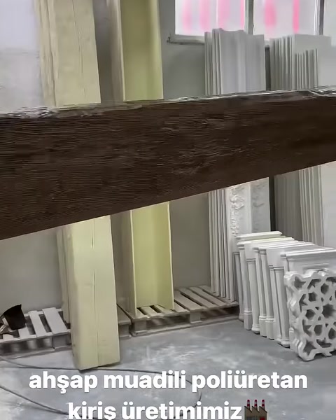 Boyanmış kütük görünümlü kiriş dikey destekler üzerinde sergileniyor