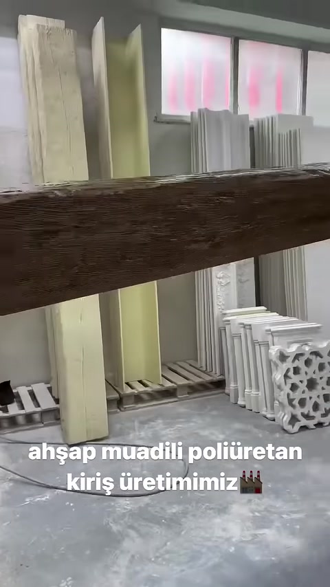 Ahşap dokulu dekoratif kiriş çalışan tarafından yatay tutuluyor