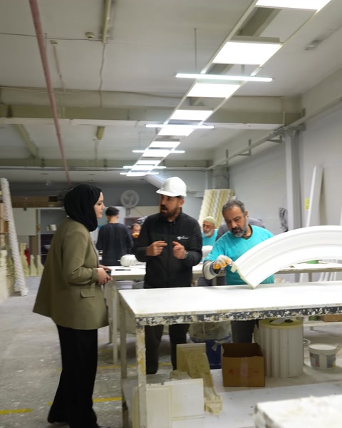 Masada kavisli kartonpiyer parçasını inceleyen çalışanlar