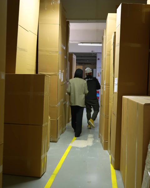 Koridorda kartonlanmış ürünlerle yürüyen çalışanlar