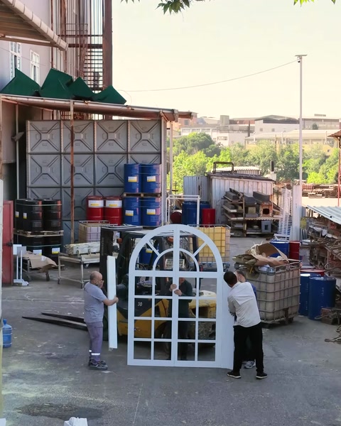 İşçiler kemerli pencere sövesini fabrika alanında taşıyor