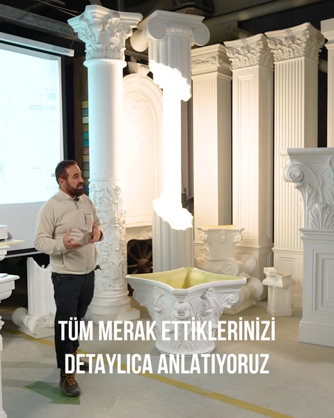 Sunucu şömine ve sütun kompozisyonunun bulunduğu salonda anlatım yapıyor